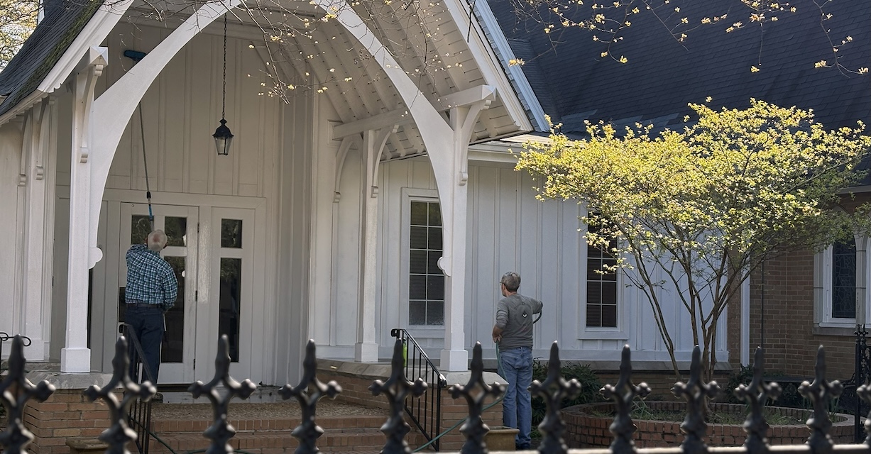 Two volunteers at work washing the church exterior.